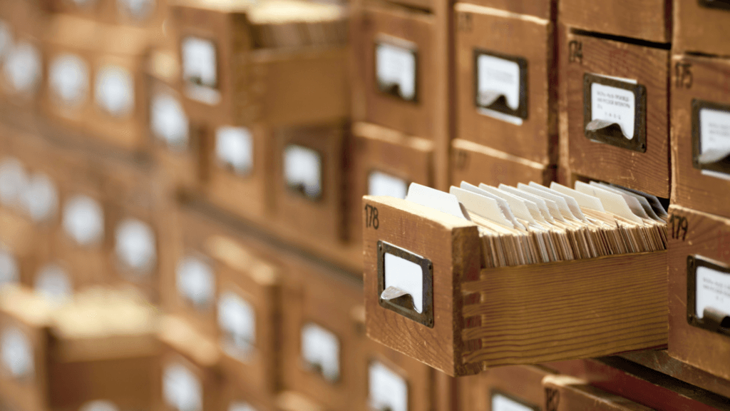 Large bank of drawers holding record cards with one draw open showing full stack of record cards.